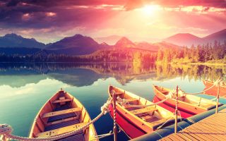 лодки на озере, фото с видом на горы, лес и закат солнца среди туч