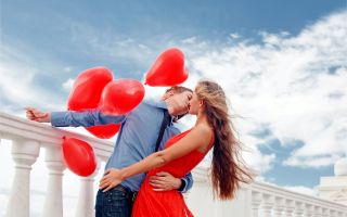 парень с воздушными шариками в руке целует девушку
