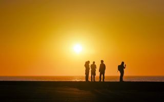 путешественники, туристы, люди на фоне желтого неба на закате