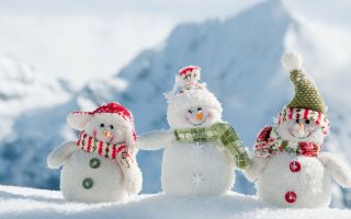 три веселых снеговика на фоне заснеженных гор