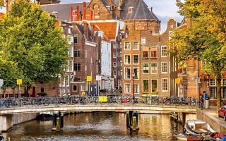 Амстердам, велосипеды на мосту на фоне домов