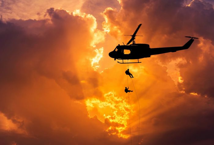 Картинка с вертолета спускаются люди по канату на фоне зарева в небе