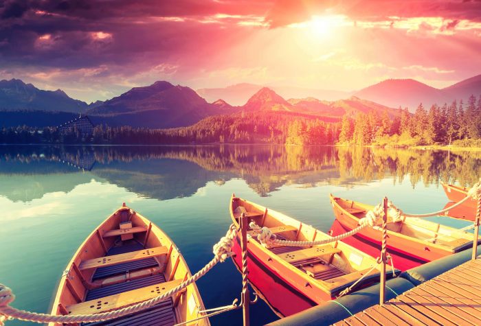 Картинка лодки на озере, фото с видом на горы, лес и закат солнца среди туч