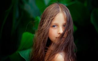 фото девочки шатенки, портрет ребенка возле зеленых листьев