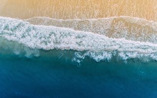 волны океана омывают песчаный берег пляжа